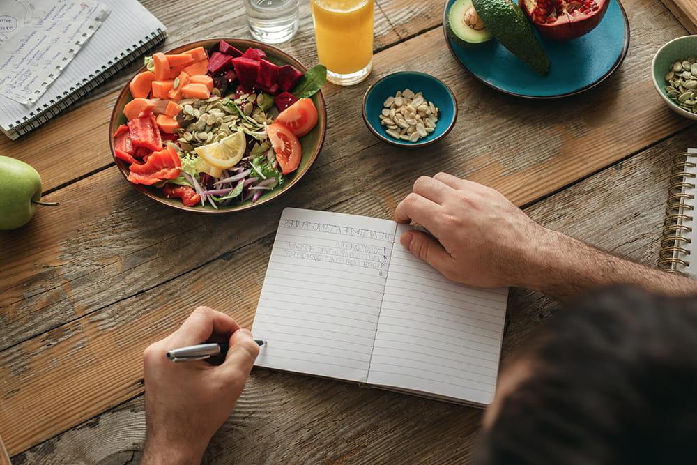 man planning meals at table with food